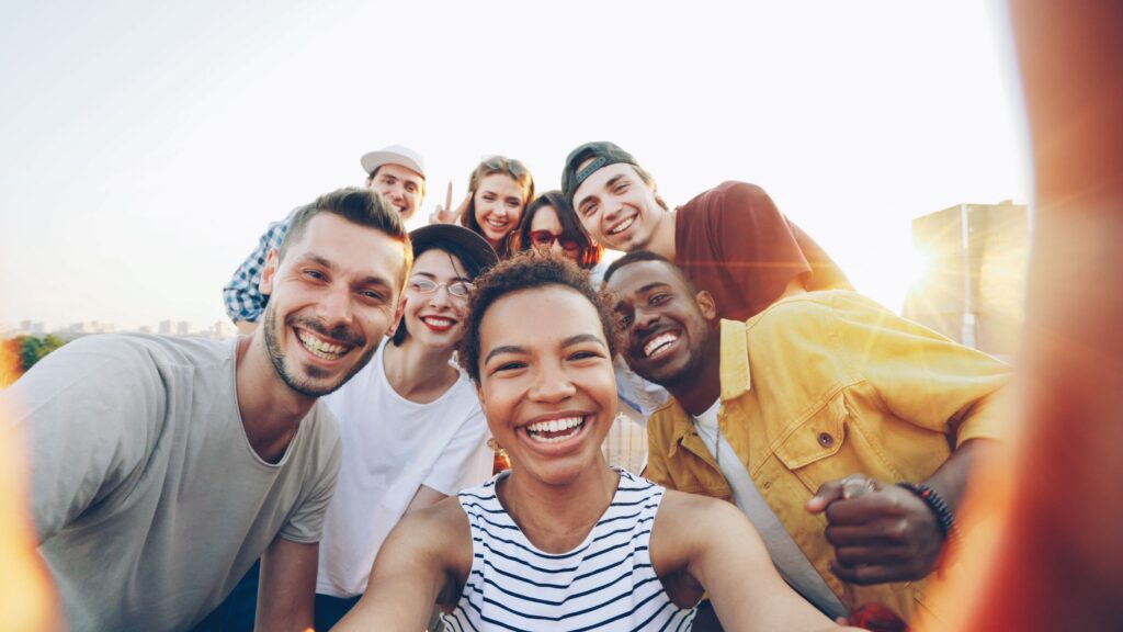 Home A diverse group of friends taking a joyful selfie outdoors during sunset.